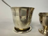a silver cup with a spoon in it next to a silver cup