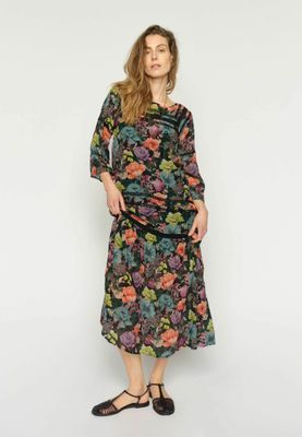 a woman wearing a black floral dress and black shoes