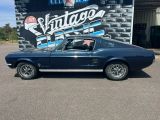 une Mustang bleue garée devant un magasin de voitures anciennes