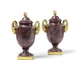 paire d'urnes antiques en bronze munies d'anses, posées sur des socles, sur fond blanc