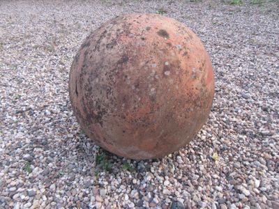une grosse balle posée par terre au milieu d'une aire de gravier