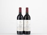 two bottles of red wine sitting on top of a white table