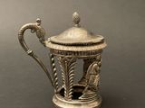 a silver teapot with a bird on top of it