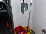 une serpillière et un seau dans un coin de la salle de bains
