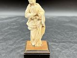 une figurine ancienne en ivoire sculpté représentant une femme tenant un panier
