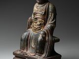 a statue of a man sitting on top of a wooden stand