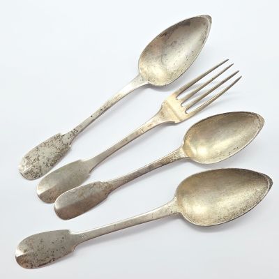 quatre cuillères et une fourchette en argent sur une surface blanche
