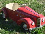 a red toy car that is sitting in the grass