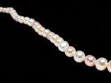 a close up of a pearl necklace on a black background