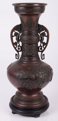 un grand vase brun orné d'une poignée en forme de dragon
