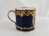 a close up of a blue and gold coffee cup on a white surface