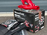 un ventilateur rouge posé sur une boîte, à côté d'un parapluie noir