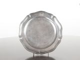 une assiette en argent posée sur un support, sur une table