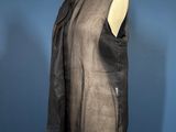 a black leather vest on a mannequin stand against a blue wall