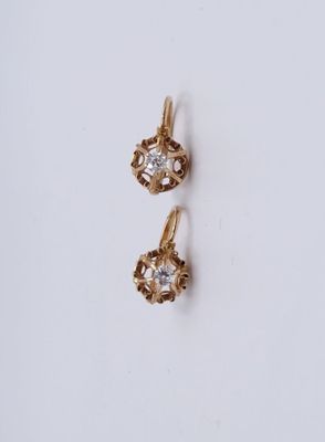 une paire de boucles d'oreilles en or sur une surface blanche