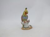 a small figurine of a bird sitting on top of a cup
