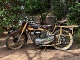 une moto garée sur la terre battue près de quelques arbres