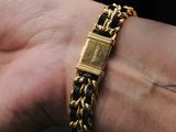 a person wearing a gold bracelet with a black and gold chain