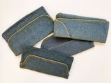 quatre morceaux de denim bleu ornés de coutures jaunes, posés sur un fond blanc