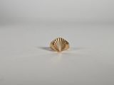 une bague en forme de coquillage dorée sur un fond blanc