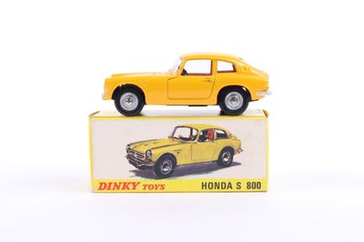 yellow toy car sitting on top of a box on a white surface