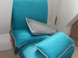 une chaise bleue sur laquelle est posé un coussin, dans un coin de la pièce
