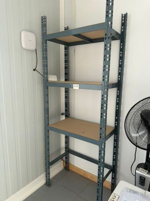a small room with a fan and shelves in it