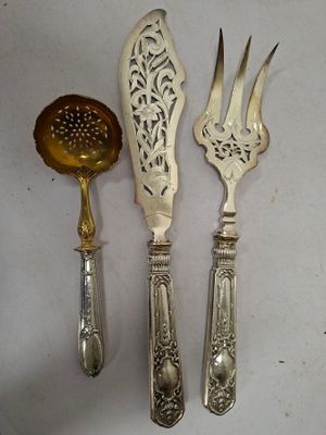 trois cuillères en argent et deux fourchettes, surmontées d'une passoire