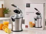 un extracteur de jus posé sur un plan de travail, à côté d'un verre de jus d'orange