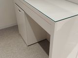 a white desk with a glass top in the corner of a room