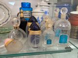 de nombreux flacons de parfum posés sur une étagère en verre