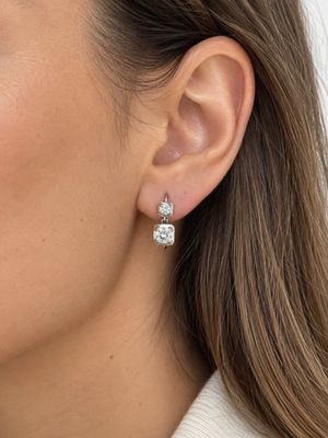 La femme porte une paire de boucles d'oreilles et un pull blanc.