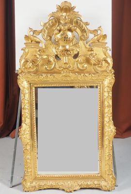 un miroir posé sur un pied, avec un rideau rouge en arrière-plan