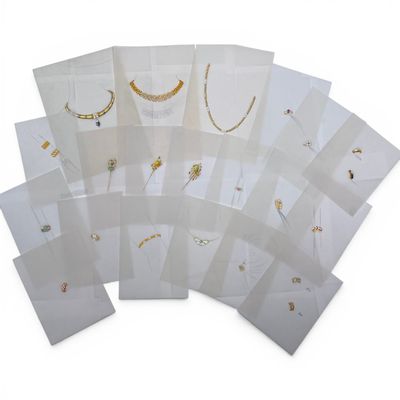 a bunch of white cards with gold jewelry on them