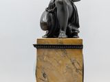 statue of a man sitting on a marble pedestal with his arms crossed