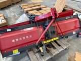 une machine rouge posée sur une palette dans un entrepôt
