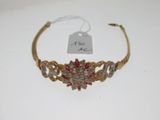 a close up of a gold headband with red and white stones
