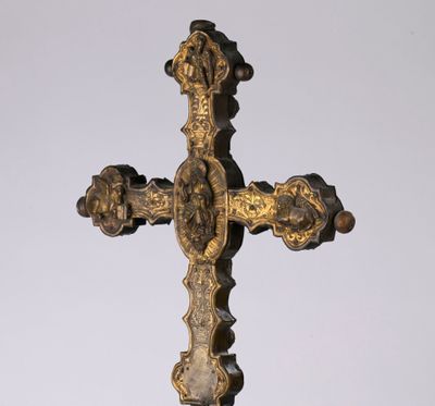 une croix en or posée sur un socle, sur fond blanc