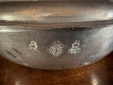 a silver bowl on a wooden table with a silver lid