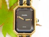 a gold watch with a black face on a chain