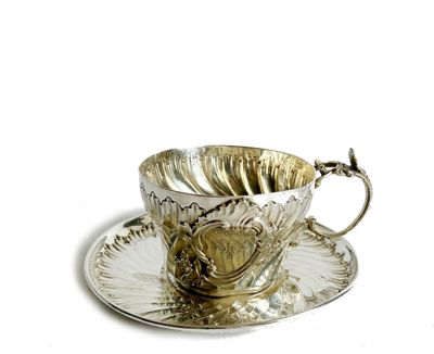 une tasse à thé en argent et sa soucoupe, posées sur une soucoupe
