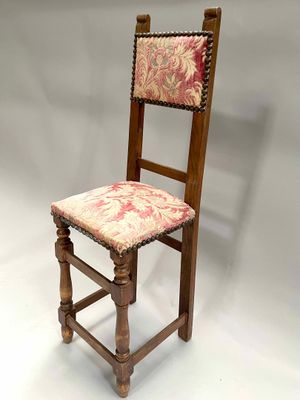 an old wooden chair with a floral upholstered seat on a white background