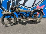 une vieille moto garée devant un mur recouvert de graffitis