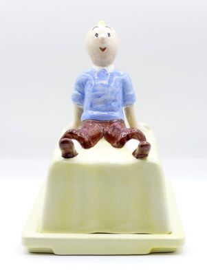 une petite figurine représentant un homme assis sur un gâteau