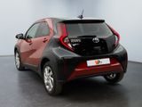 the rear of a red and black toyota c - hr parked in a room