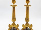 paire de bougeoirs anciens en laiton reposant sur des socles en marbre noir