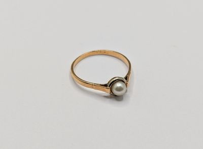 Gros plan sur une bague en or ornée d'une perle