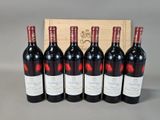 six bottles of red wine are lined up in front of a wooden box