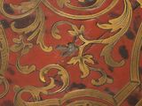 a red and gold plate with gold designs on it