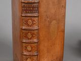 an old book sitting on top of a wooden table next to a vase